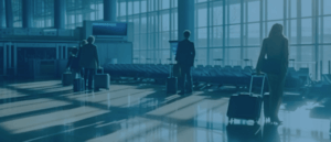 Image of travelers walking with carry-on suitcases toward a gate at the airport.